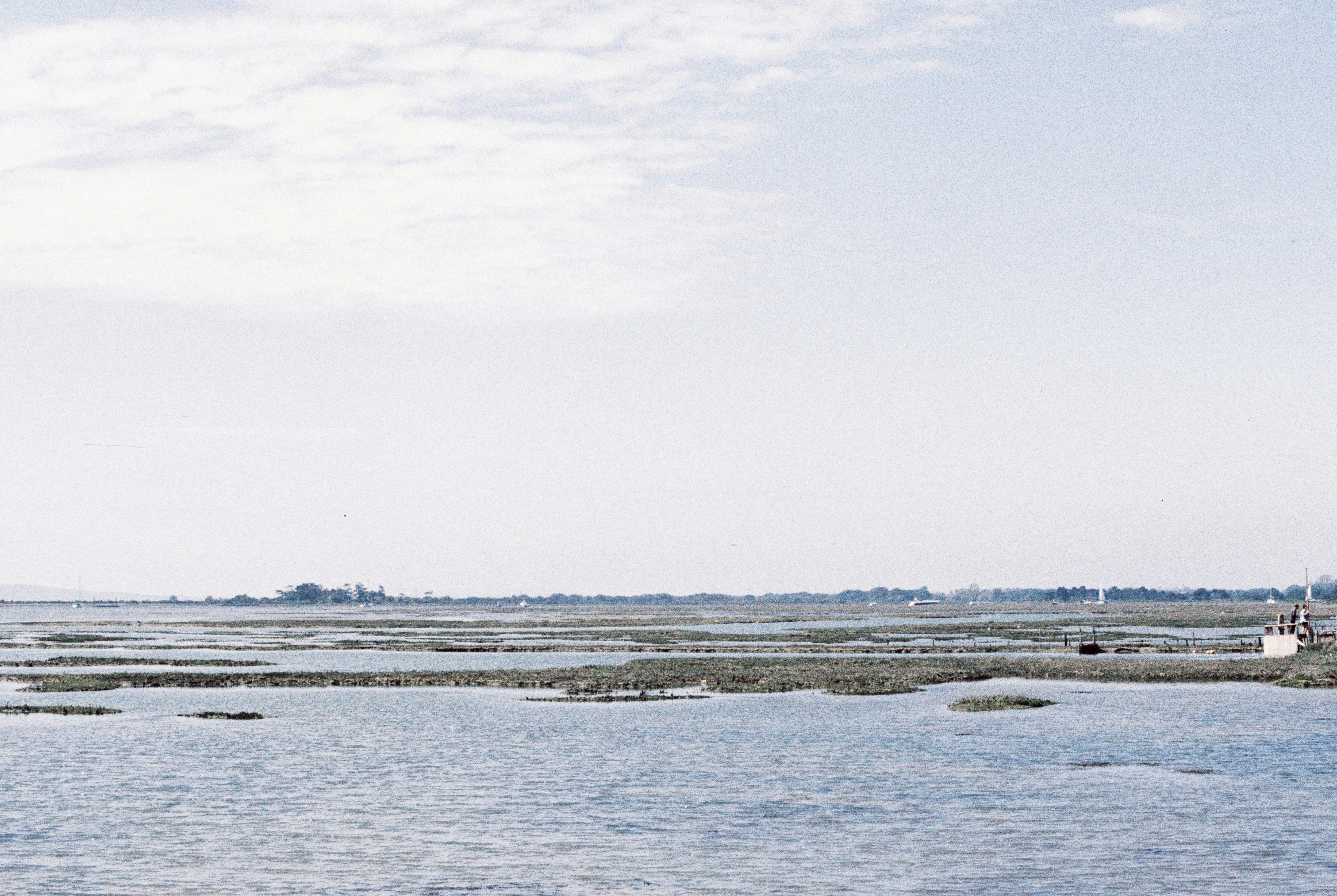 body of water under white sky during daytime